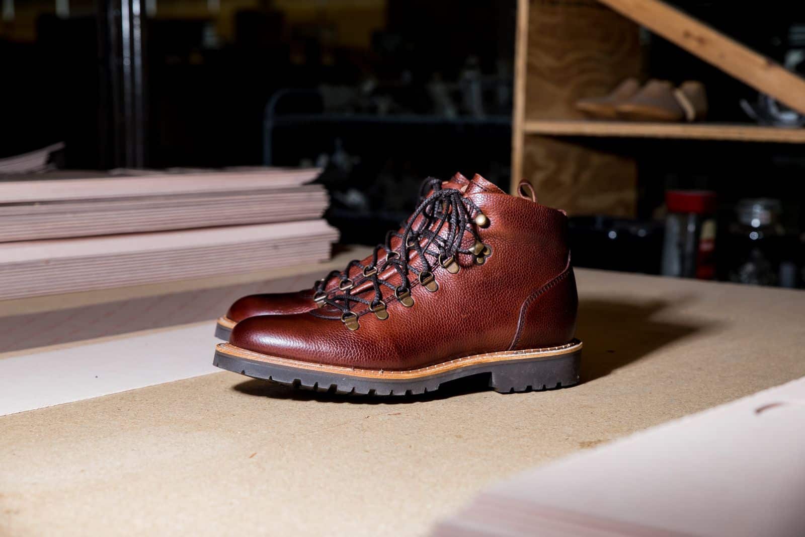 Brown leather boots with a heavy rugged sole resting on a workshop table