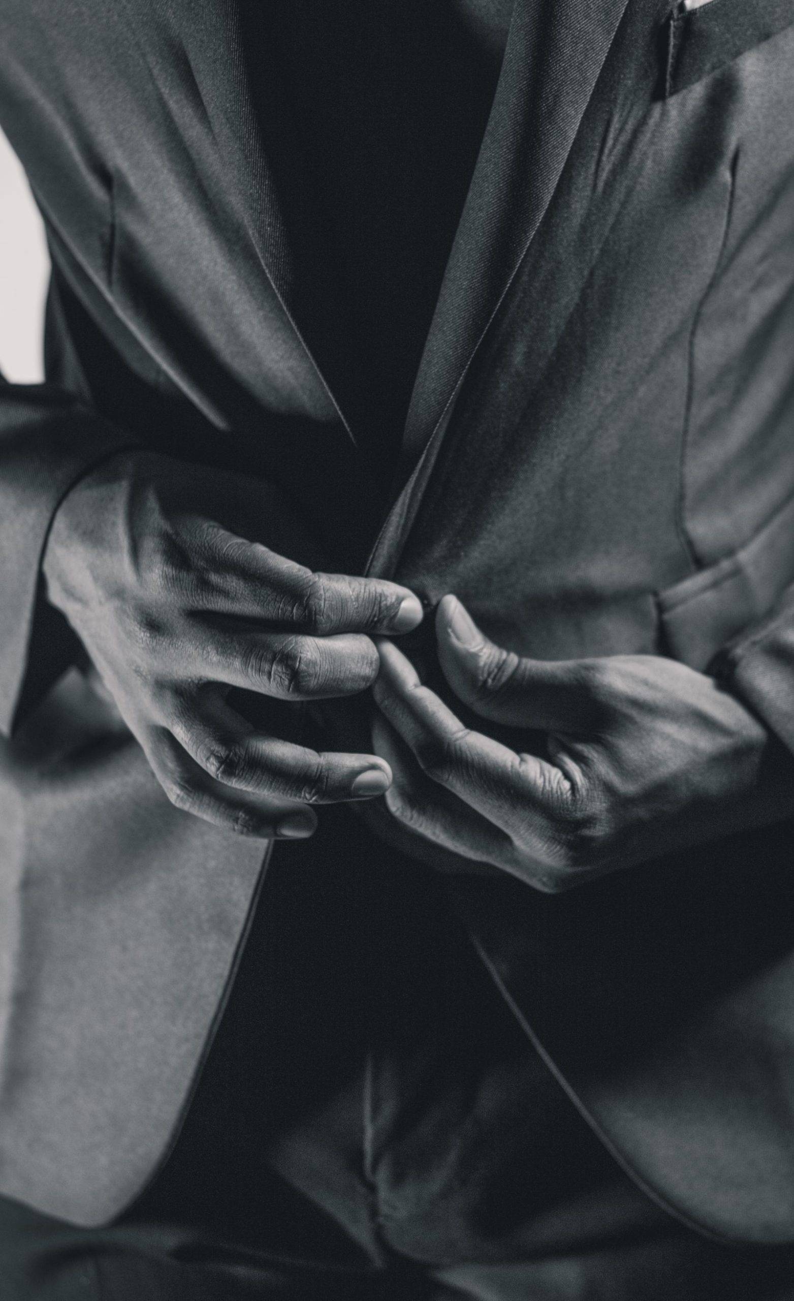 Man fastening the button of a black suit jacket