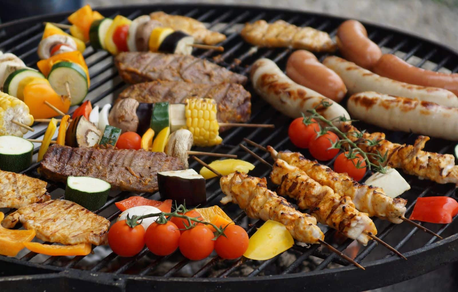 Sausages, meat and vegetables cooking on a charcoal grill