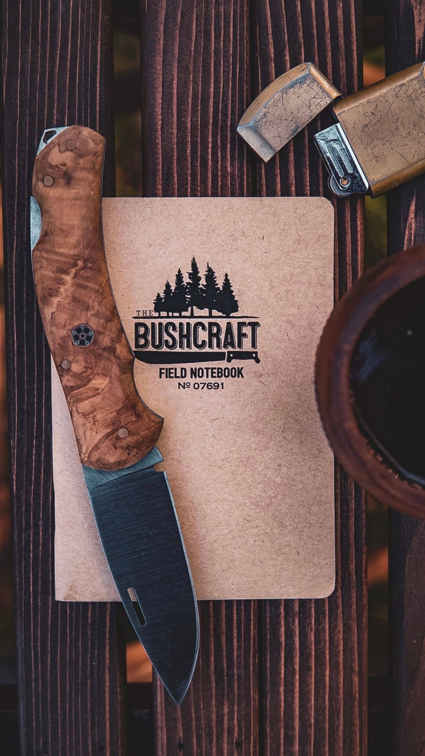 Folding pocket knife and lighter resting on a field notebook