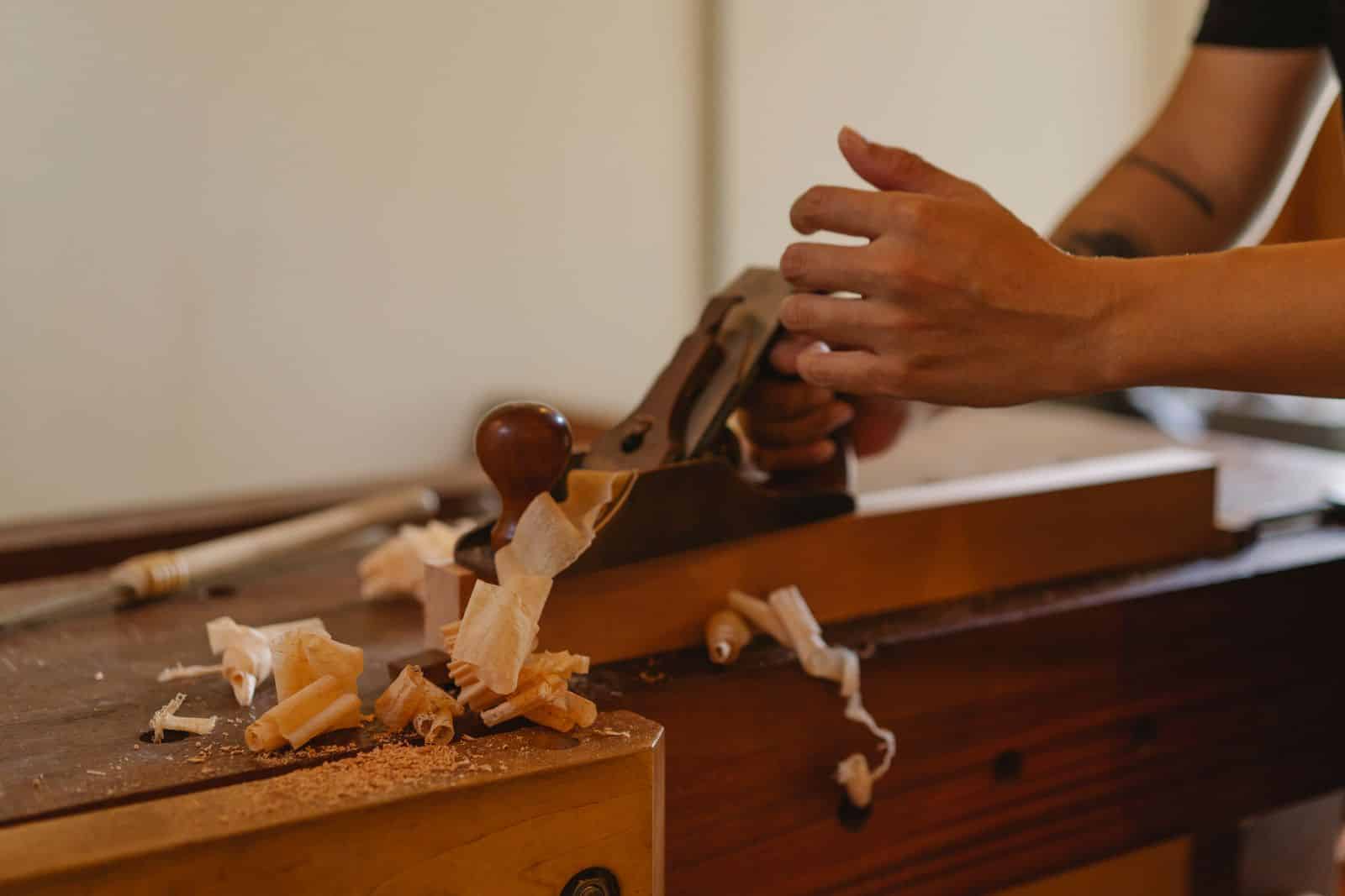 Woodworker planing a board with a hand plane in a workshop